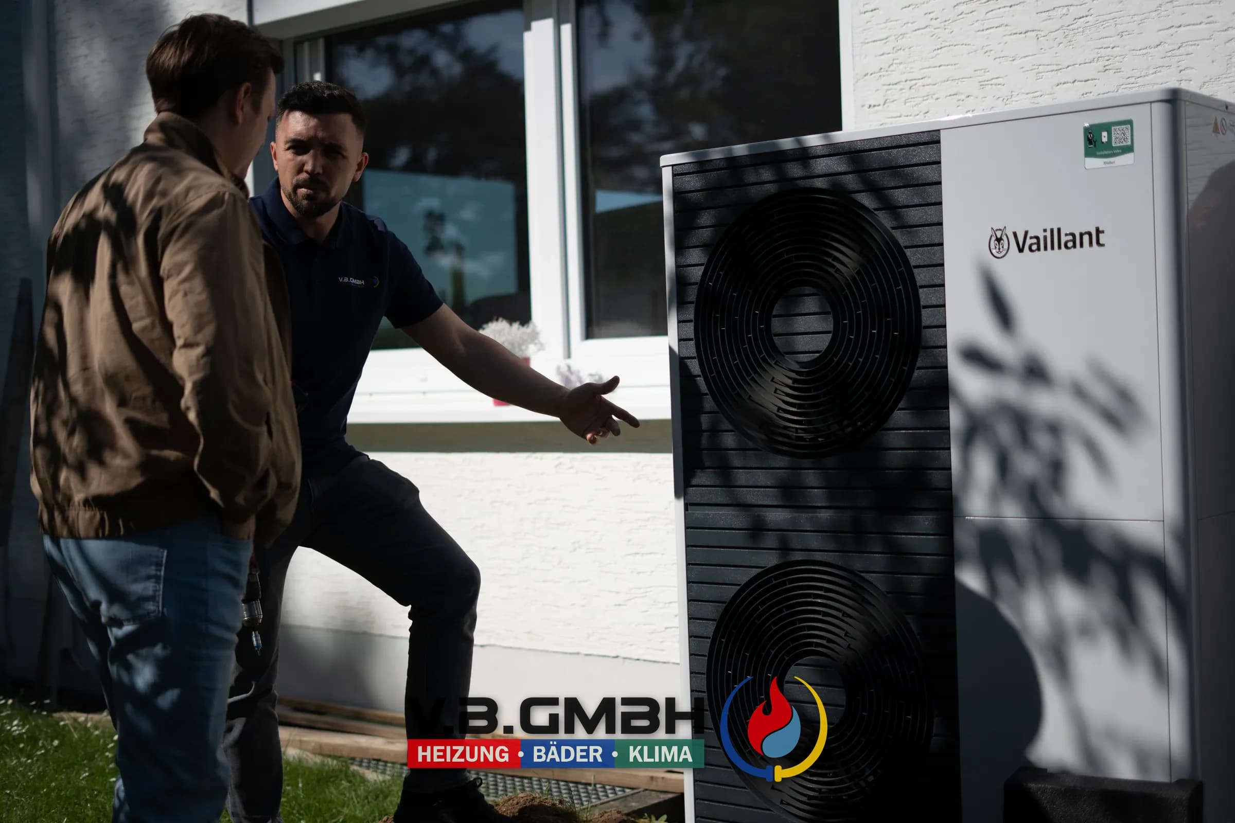 Monteur präsentiert große Vaillant Wärmepumpe an Hausseite