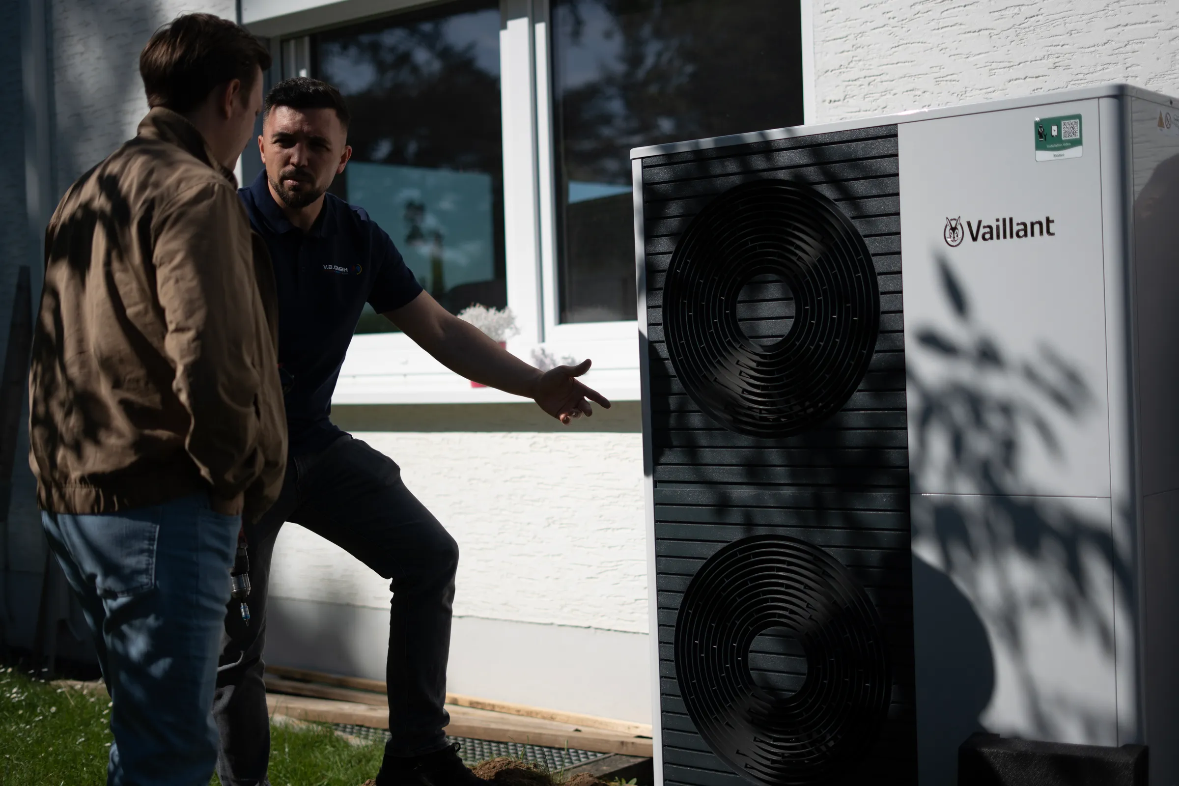 Monteur präsentiert große Vaillant Wärmepumpe an Hausseite