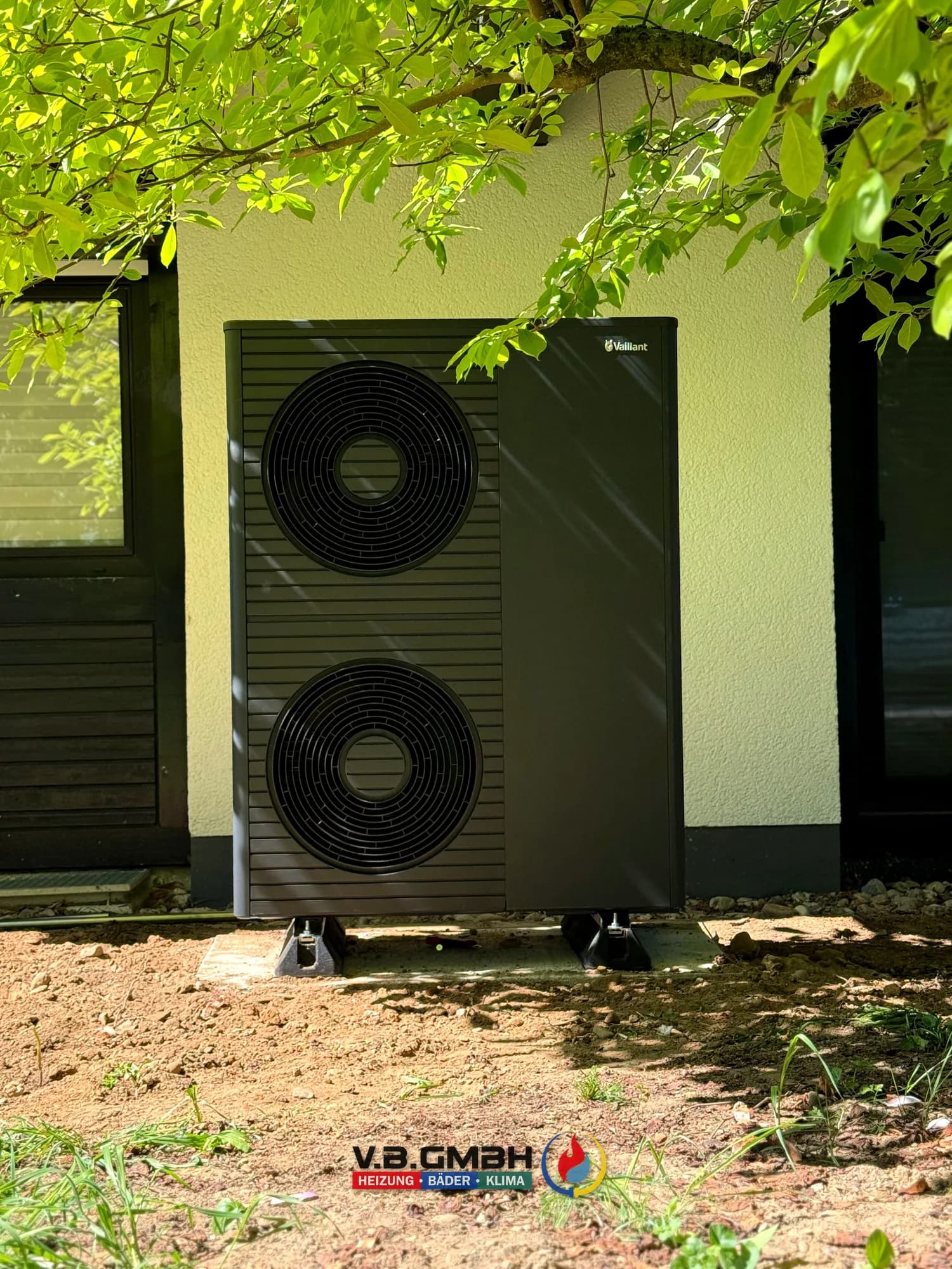 Große Vaillant Wärmepumpe mit zwei Ventilatoren im Grünen an der Hauswand aufgestellt