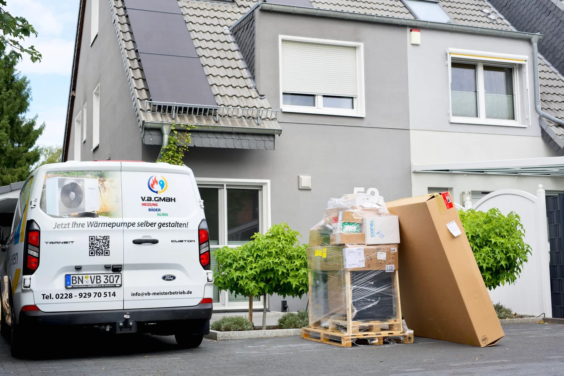 V.B. GmbH Transporter vor einem Kundenhaus in Bonn, daneben die angelieferte Wärmepumpe auf der Palette