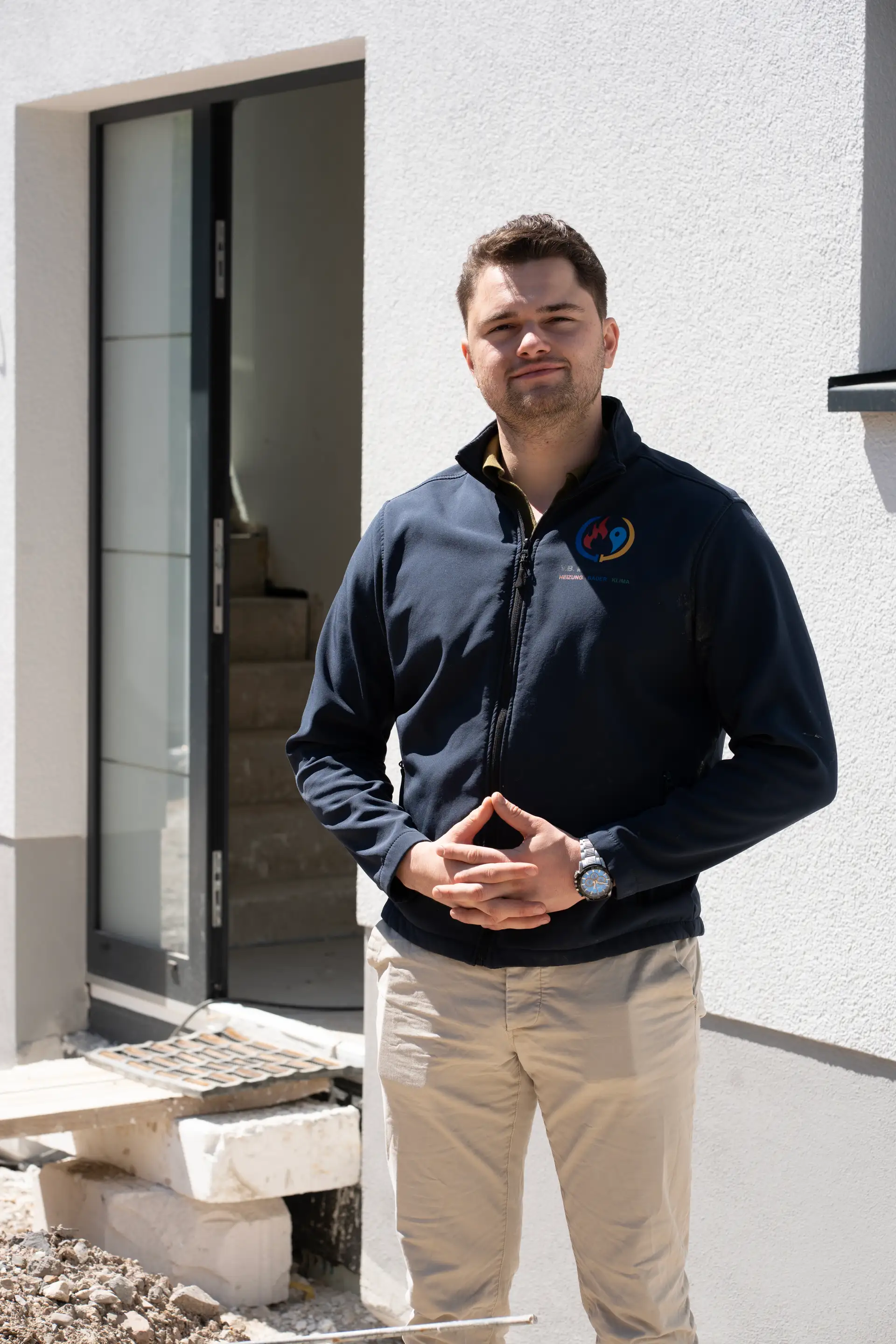 VB-Mitarbeiter Portrait in Firmenjacke vor Hauseingang