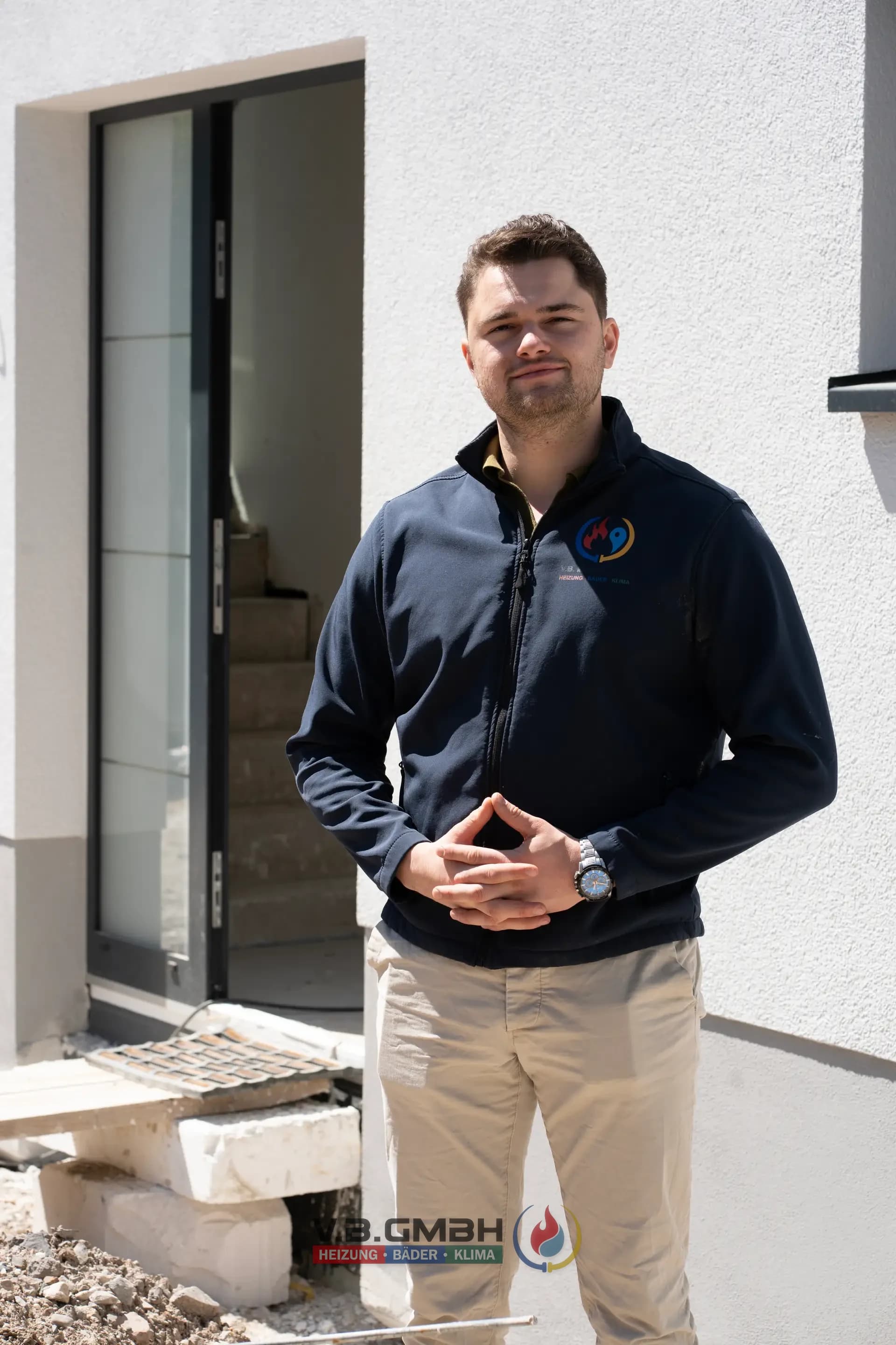 VB-Mitarbeiter Portrait in Firmenjacke vor Hauseingang