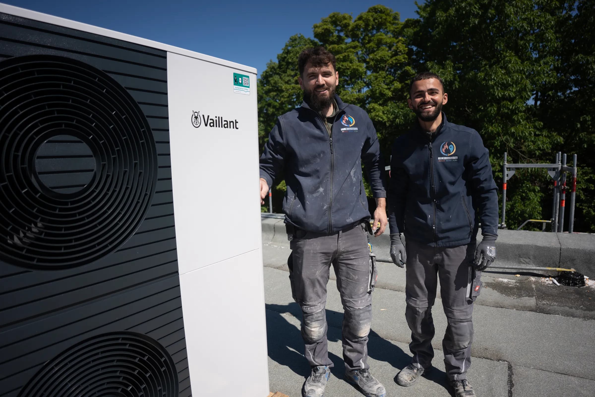 Zwei Monteure vor fertig installierter Vaillant Wärmepumpe auf Flachdach