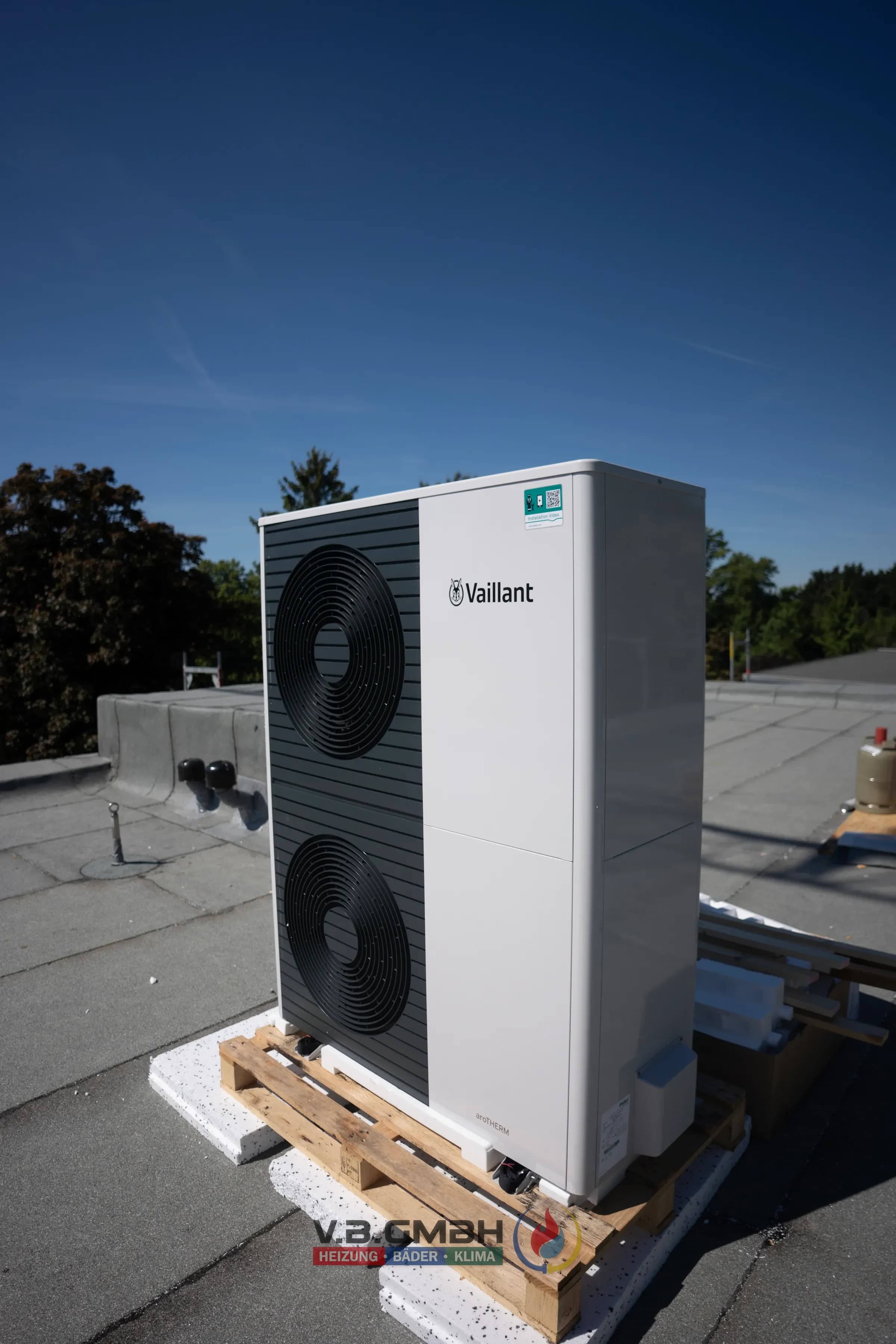 Vaillant Wärmepumpe Außeneinheit auf Flachdach vor blauem Himmel