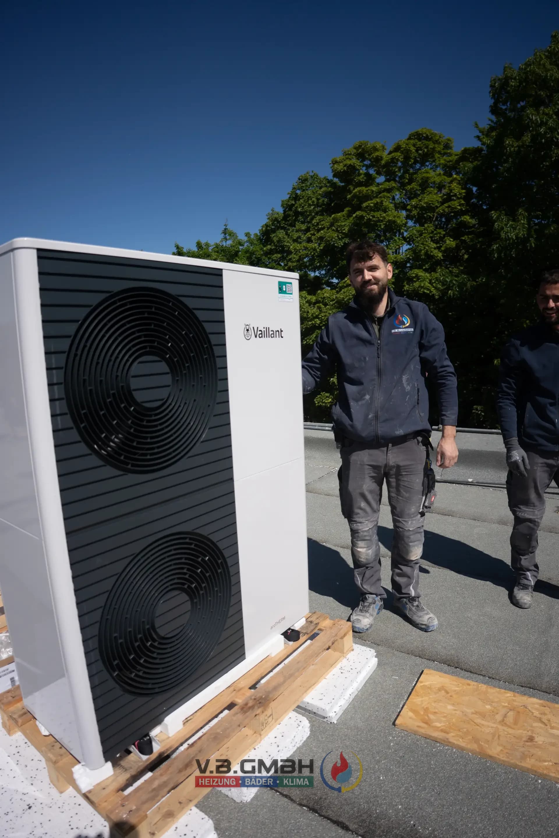 Monteur neben fertig installierter Vaillant Wärmepumpe auf Dach