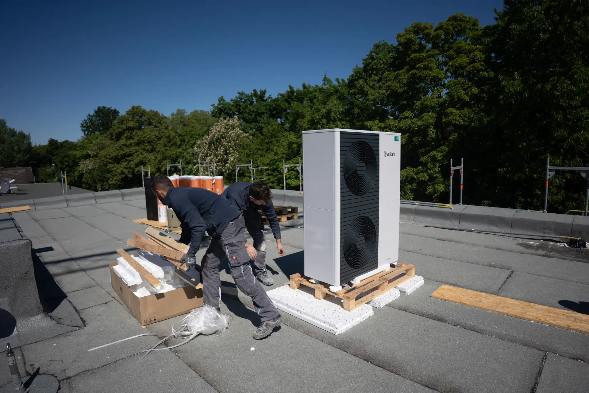 Zwei Monteure installieren Vaillant Wärmepumpe auf Flachdach