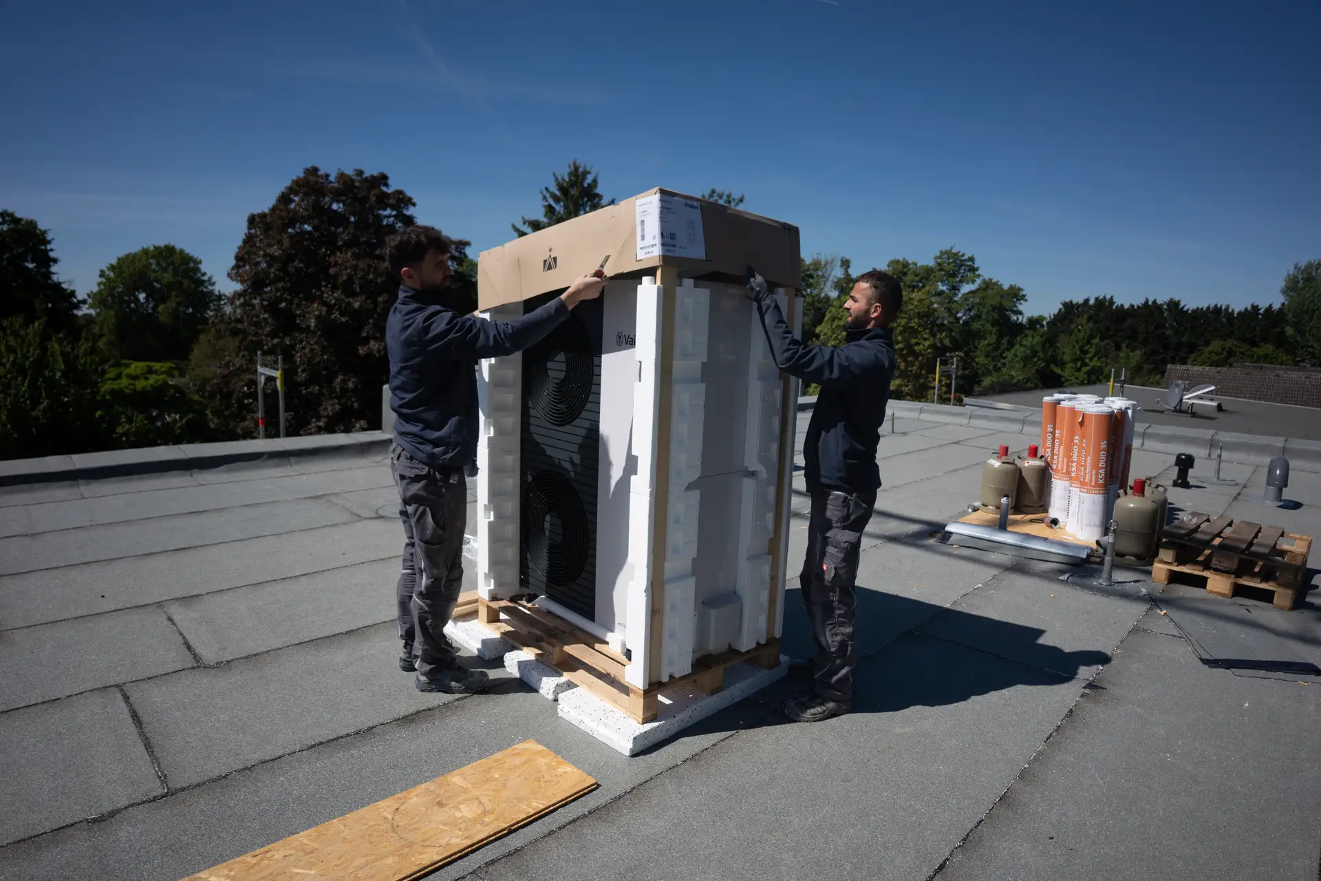 Zwei Monteure installieren Wärmepumpe auf Flachdach