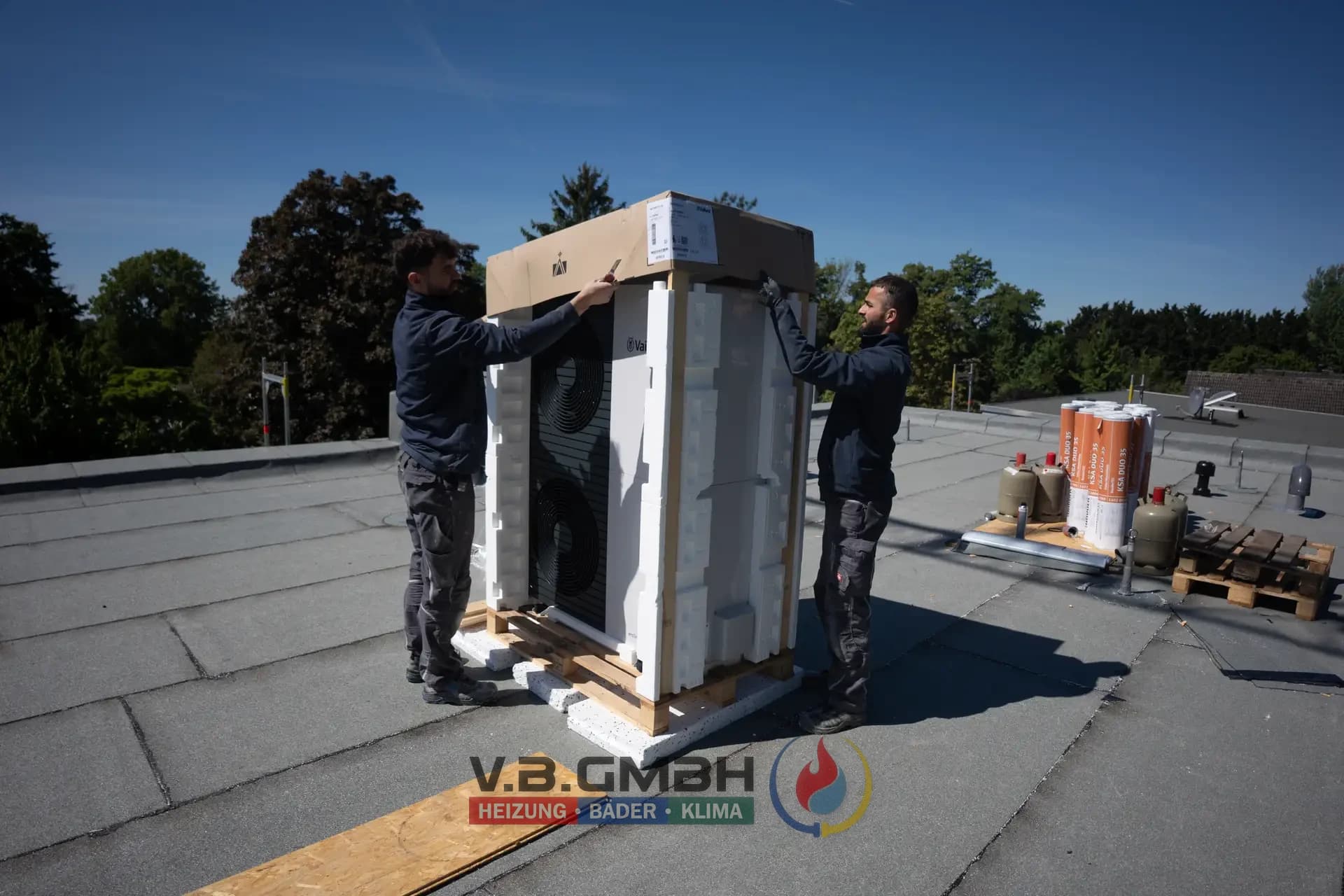 Zwei Monteure installieren Wärmepumpe auf Flachdach