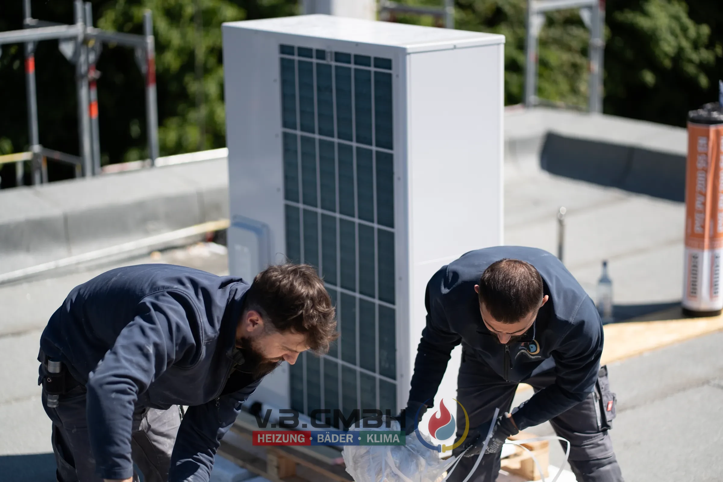 Zwei Monteure installieren gemeinsam Wärmepumpe auf Flachdach